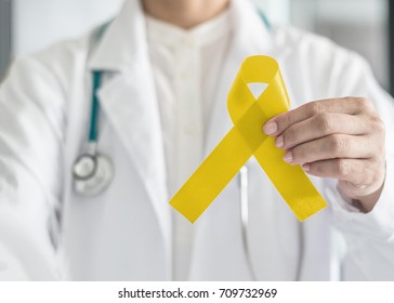 Yellow ribbon symbolic color for Sarcoma Bone cancer, Bladder health, Liver disease, Spina Bifida Awareness Month and suicide prevention in doctor's hand