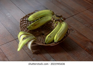 Yellow ripe bananas are placed in a basket, on a board.
