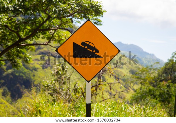 Yellow road\
sign car down. Steep descent of the\
road