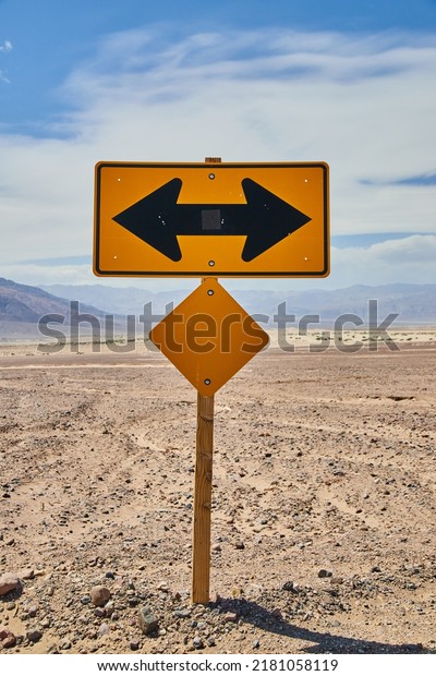 Yellow road sign T intersection left or right in\
sandy desert