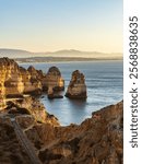 Yellow rocks and cliffs washed by the waters of a blue sea at sunrise in Algarve, Portugal