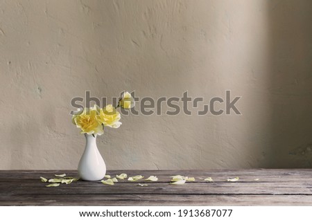 yellow roses in white vase on background wall