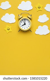 Yellow Round Alarm Clock, Moon, Stars And White Clouds On The Yellow Background.