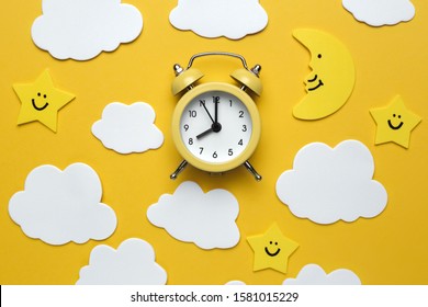 Yellow Round Alarm Clock, Moon, Stars And White Clouds On The Yellow Background.