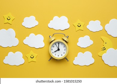 Yellow Round Alarm Clock, Moon, Stars And White Clouds On The Yellow Background.