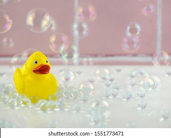 Yellow rubber duck in bathroom with bubbles and pink tiles