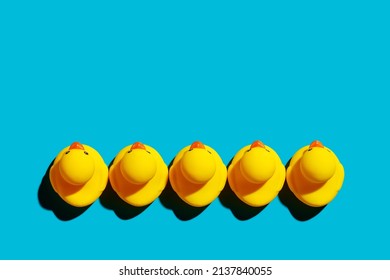 Yellow Rubber Ducks Arranged In A Row On Blue Background. Business Team Startup Equality Concept.