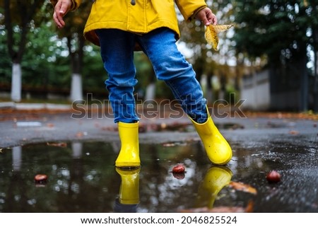 Similar – Image, Stock Photo Small infant boy wearing yellow rubber boots and yellow waterproof raincoat standing in puddle on a overcast rainy day. Child in the rain.