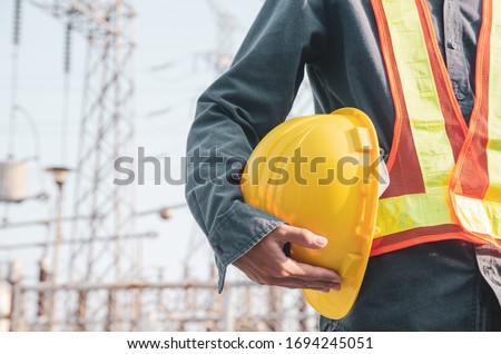 Yellow safety helmet is in the hands of an electrician.