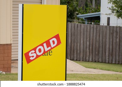 Yellow For Sale Sign Near The Resedential Building House With Sold Sticker On It