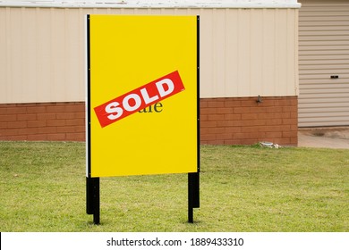 Yellow For Sale Sign Near The Resedential Building House With Sold Sticker On It