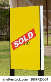 Yellow For Sale Sign Near The Resedential Building House With Sold Sticker On It