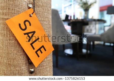 A yellow SALE tag on the sofa, with blurred furniture in the background, concept of store price discount marketing strategy to boost sales