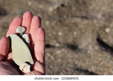 Yellow sand, colorful pebbles on the coastline, shadowy sea stones background on the beach. woman's hand with seastones on the beach - Shutterstock ID 2218684531