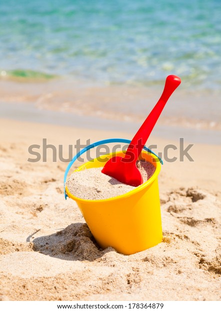 Yellow sand pail and\
shovel on a beach