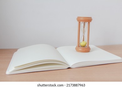 Yellow Sand running through the bulbs of an hourglass on noteboo