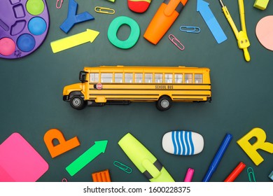 Yellow school bus and stationery on green background, flat lay. Transport for students - Shutterstock ID 1600228375