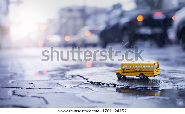 Yellow school bus (toy model) during hard\
rain fall in city,low angle view and shallow depth of field\
composition.Back to school concept\
background.