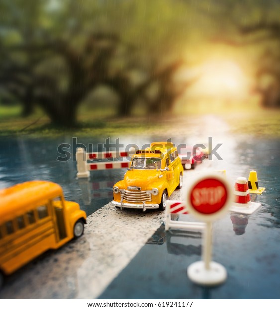 Yellow\
school bus (toy model) crossing through the country road.Travel /\
Education / Transportation concept\
background.