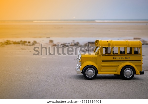 Yellow school bus toys on the beach, school bus\
helps to pick up and send all children to school safely and on\
time.\
Back to school\
conncept.