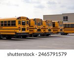 Yellow school buses lined up in a parking lot - SCHOOL BUS signage - safety warnings and signals - building in background. Taken in Toronto, Canada.