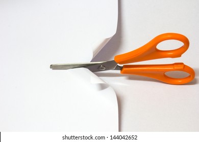 Yellow scissor cutting white paper on white background