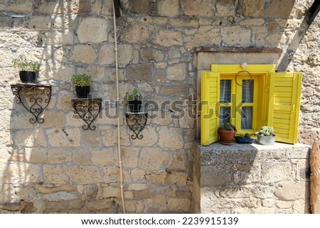 Yellow shutter window and stone house. Fancy and well decorated stone house with colorful shutter and well designed pots and plants. Lifestyle concept and idea.