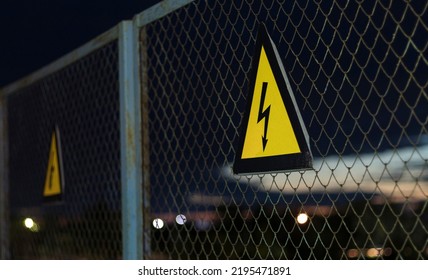 yellow sign high voltage on the fence with mesh