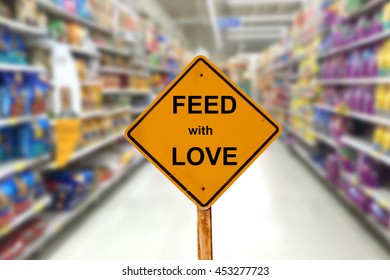 Yellow Sign With Message FEED WITH LOVE And Blur Image Of Pet Food Aisle In Super Market