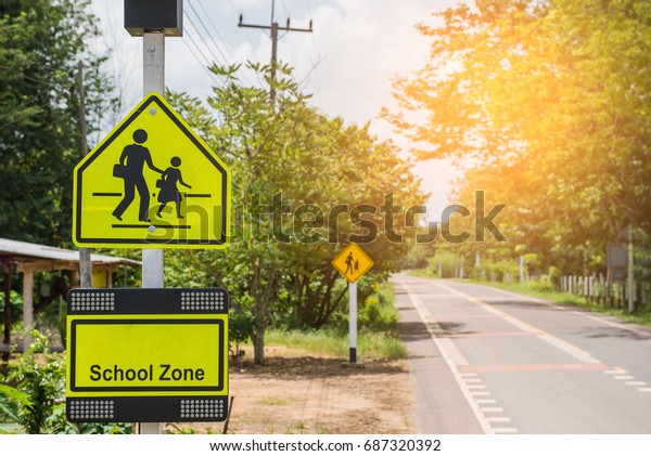 Yellow sign\
school zone symbol in the countryside\
.