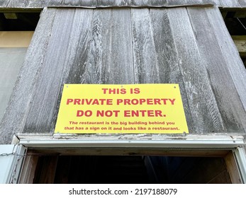 A yellow sign that reads "This is private property do not enter. The restaurant is the big building behind you that has a sign on it and looks like a restaurant. - Shutterstock ID 2197188079