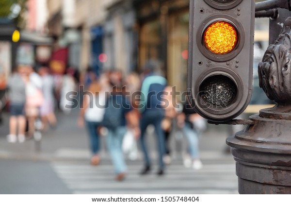 yellow signal of the traffic light with\
blurred pedestrian at the\
background