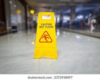 yellow signs that say wet floors or slippery floors in mall hallways and public spaces