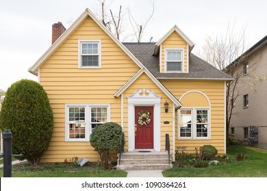 Yellow Single Family Home With Red Door And Floral Wreath