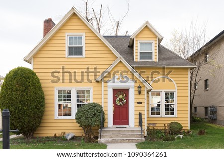 Yellow single family home with red door and floral wreath