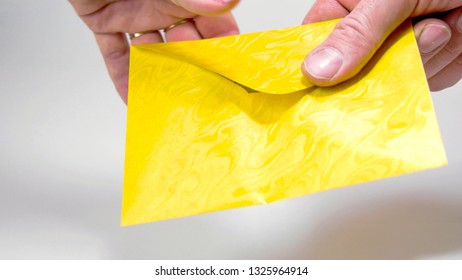 A yellow small envelope with 3 Euro bills. A mans hand showing the bills inside the envelope and giving it on the lady