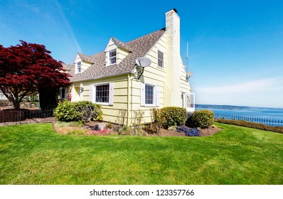 Yellow Small Home With Water View And Red Maple.