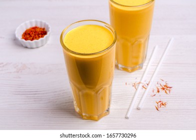 Yellow smoothie in glass on a wooden background. Selective focus.