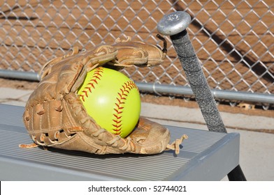 Yellow Softball, Bat, And Glove On An Aluminum Bench