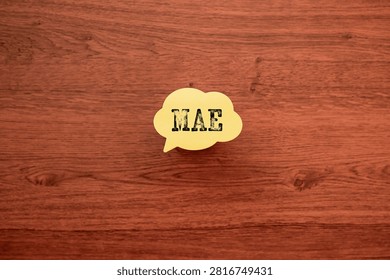 Yellow speech bubble with MAE text on wooden desk surface. Perfect eye-catcher for data science, machine learning, and business analytics content needing visual representation of statistical metrics.