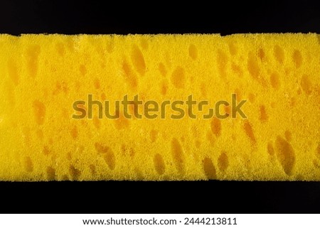 A yellow sponge with a black background. The sponge is yellow and has a lot of bumps on it