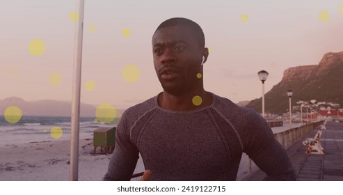 Yellow spots floating against african american fit man running on the promenade. sports, fitness and technology concept - Powered by Shutterstock