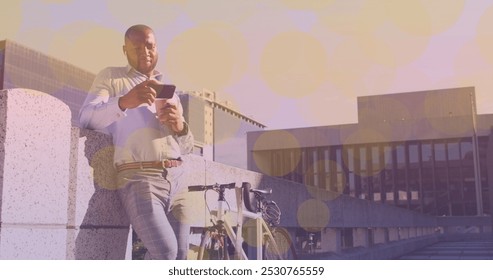 Yellow spots of light floating against african american man with a bicycle using smartphone. pedal day awareness concept - Powered by Shutterstock