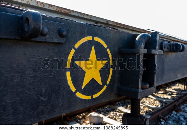 Yellow star paint on\
black steel of train.