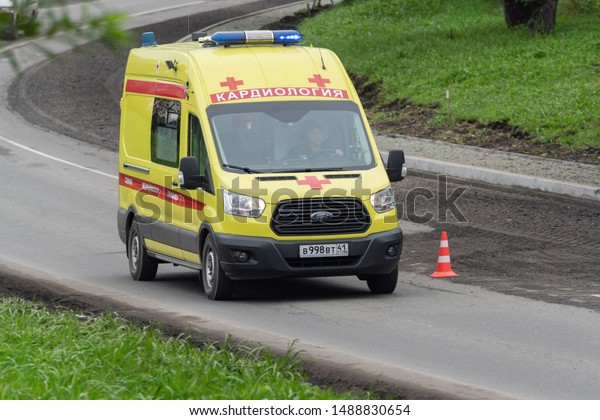 Yellow State Ambulance Cardiology van with siren and\
blue flashing lights quickly moves on city street road to help\
patient. Petropavlovsk Kamchatsky City, Kamchatka Peninsula, Russia\
- Aug 27, 2019