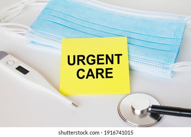 Yellow Sticker With Text Urgent Care Lying With The Mask, Stethoscope And Thermometer. Medical Concept