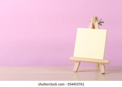 Yellow Sticky Note Book With Easel Against Pink Background.