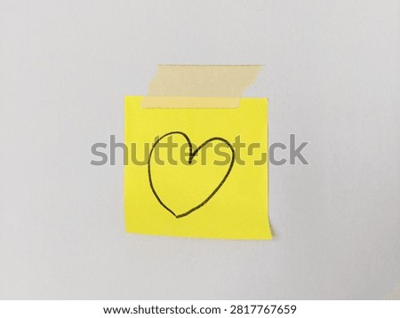 Yellow sticky note featuring hand drawn heart symbol taped to wall background with copy space, for love, Valentine's Day, anniversary, affection, relationship, romance, and romantic message concepts.