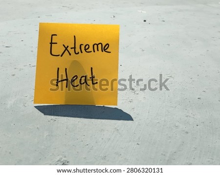 yellow sticky note with the text Extreme Heat on a sun-drenched gray concrete surface under scorching midday sunlight, conceptualizing global warming and climate change crisis