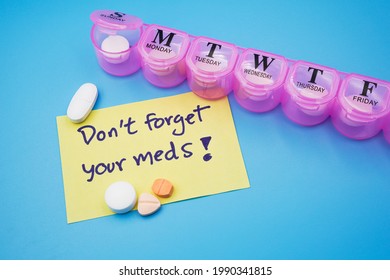 Yellow Sticky Note With Wording Don't Forget Your Meds With Medicines And Pills Organizer Box Or Tablet Case Box On Blue Background